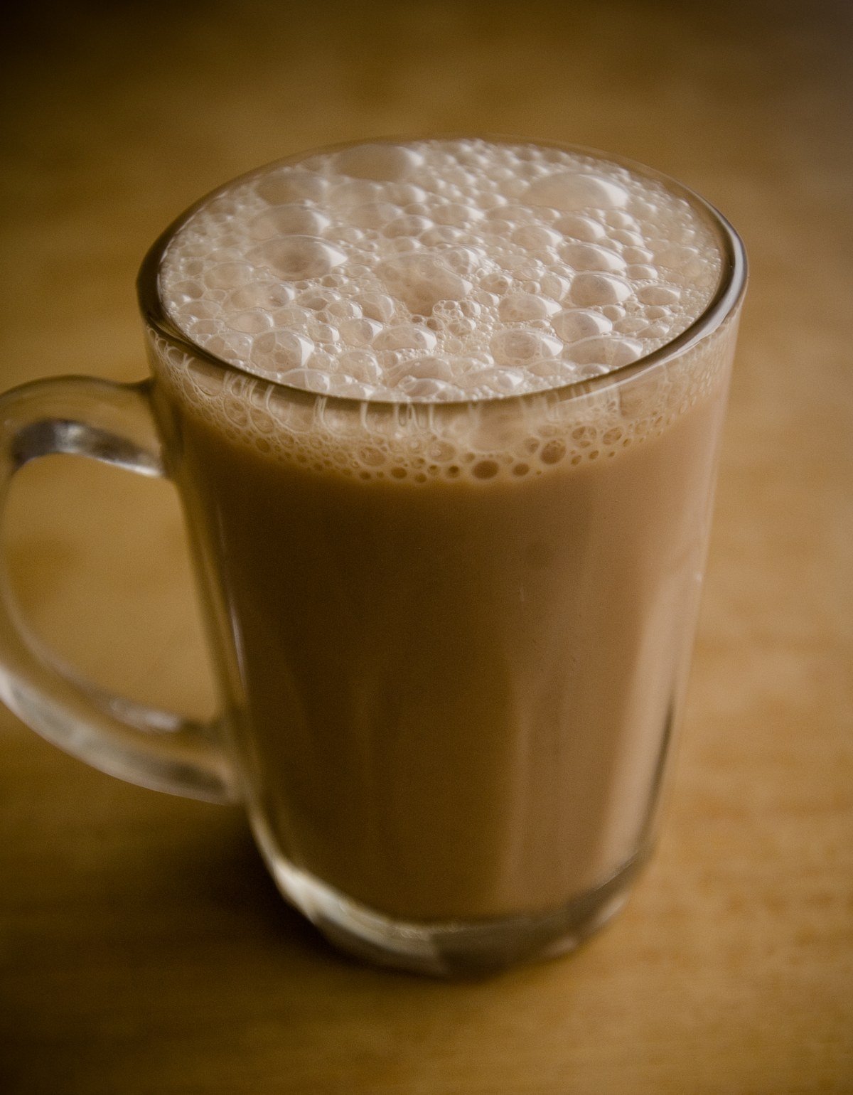 A glass of Malaysian teh tarik served on a table