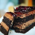 Hirisan kek coklat berlapis dengan krim coklat di atas pinggan putih