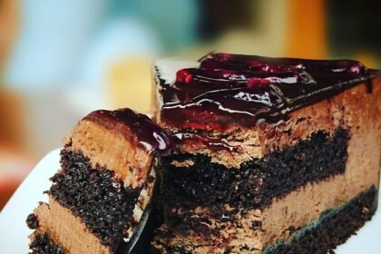 Hirisan kek coklat berlapis dengan krim coklat di atas pinggan putih