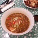 Semangkuk asam laksa dengan hirisan cili dan bunga kantan