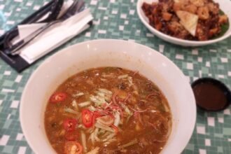 Semangkuk asam laksa dengan hirisan cili dan bunga kantan