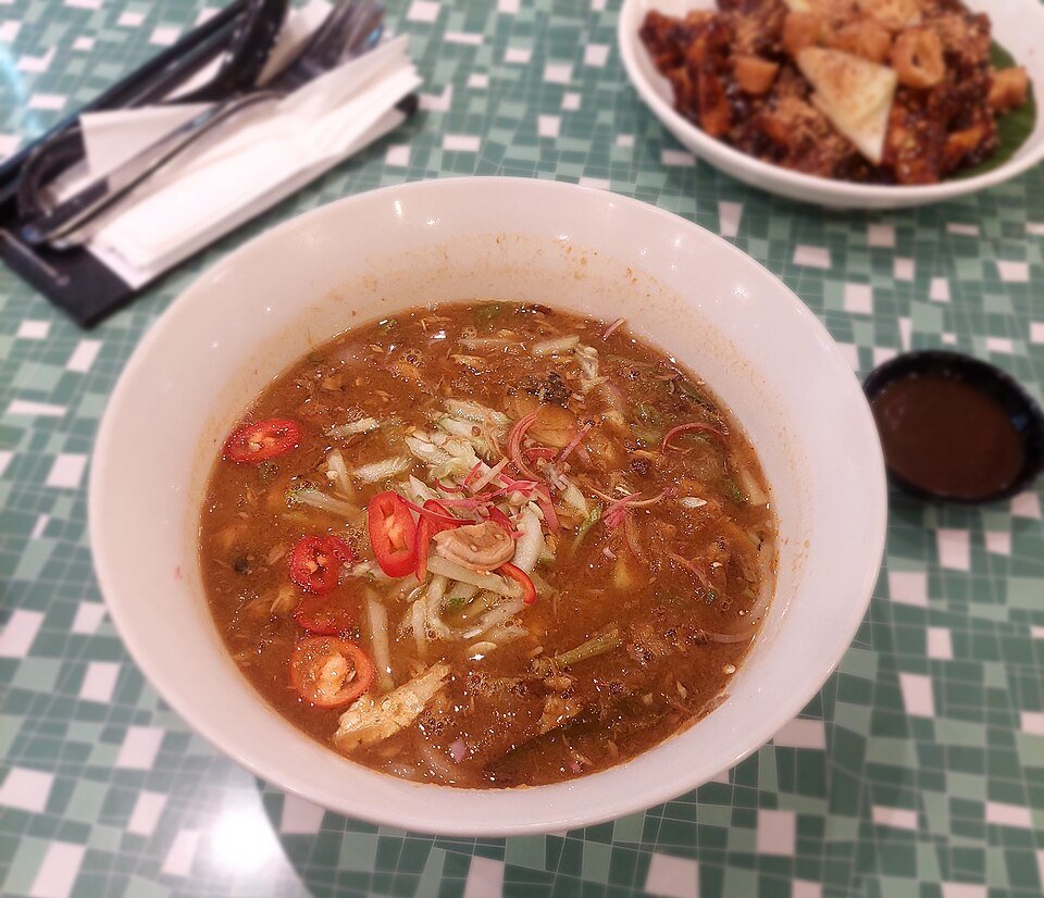 Semangkuk asam laksa dengan hirisan cili dan bunga kantan