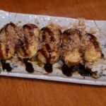 Takoyaki di atas pinggan dengan sos dan kepingan bonito