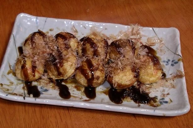 Takoyaki di atas pinggan dengan sos dan kepingan bonito