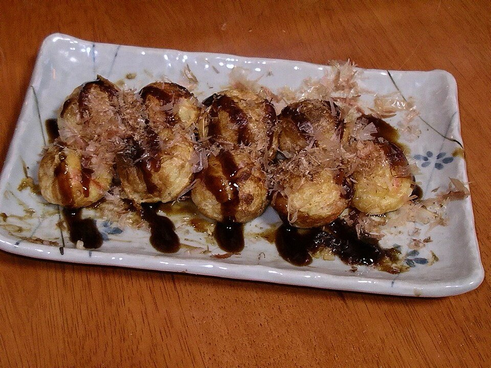 Takoyaki di atas pinggan dengan sos dan kepingan bonito
