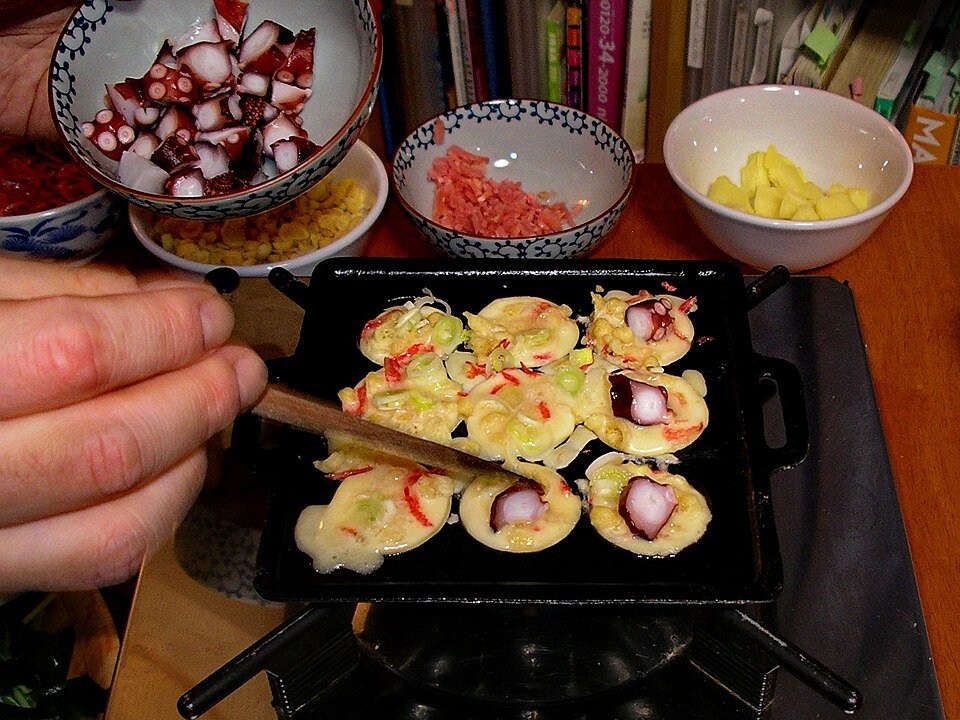 Takoyaki dimasak dalam acuan bulat dengan isi sotong kurita