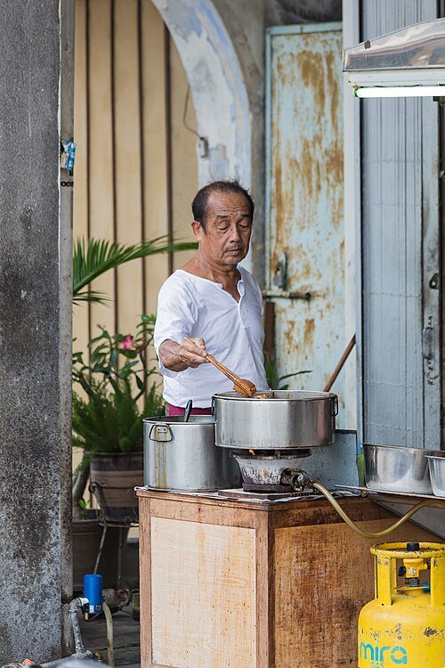 Seorang tukang masak menyediakan makanan di sebuah kedai kopi di George Town, Pulau Pinang