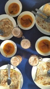 Roti canai bersama kari dan teh tarik di sebuah kedai Malaysia