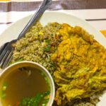 Sepinggan nasi goreng kampung dengan telur dadar dan semangkuk sup.