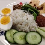 Nasi lemak buatan rumah dengan sambal, telur rebus, timun, ikan bilis dan sayur.