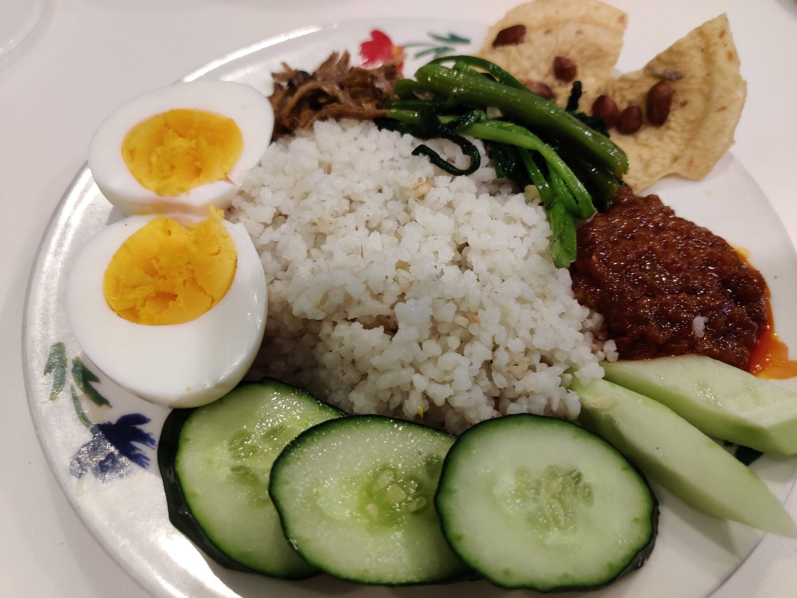 Nasi lemak buatan rumah dengan sambal, telur rebus, timun, ikan bilis dan sayur.