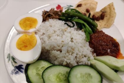 Nasi lemak buatan rumah dengan sambal, telur rebus, timun, ikan bilis dan sayur.