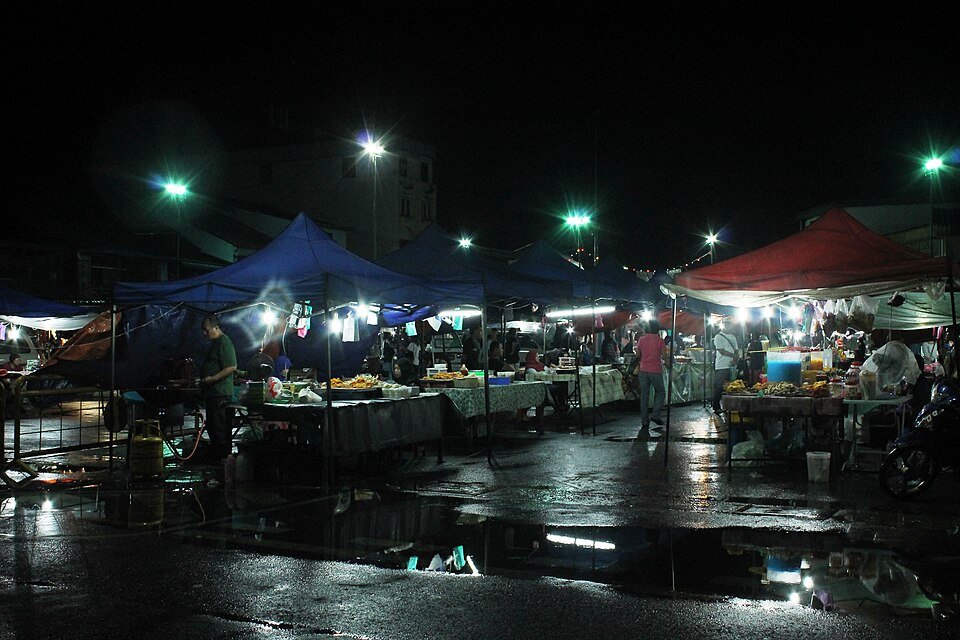 Gerai dan pengunjung di pasar malam Sibu pada waktu malam