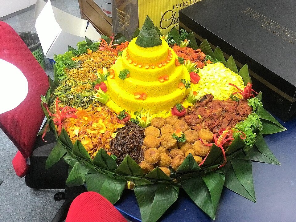 Celebratory Indonesian tumpeng with yellow rice and assorted side dishes