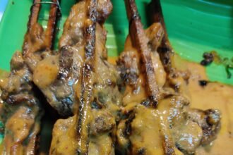 Ayam percik bersalut kuah di atas lidi pemanggang