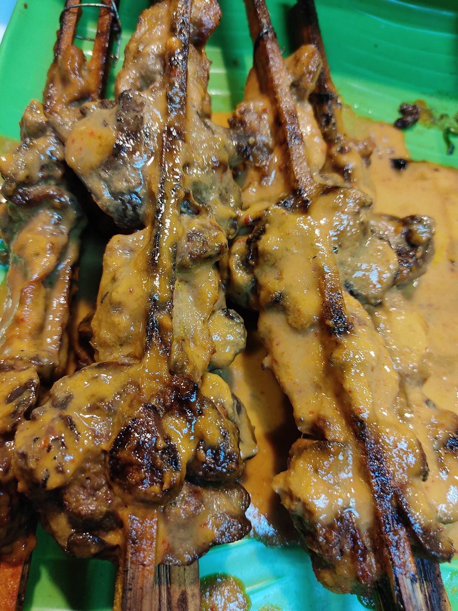 Ayam percik bersalut kuah di atas lidi pemanggang
