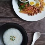 Bubur nasi Malaysia bersama telur rebus, ikan, sambal dan sayuran