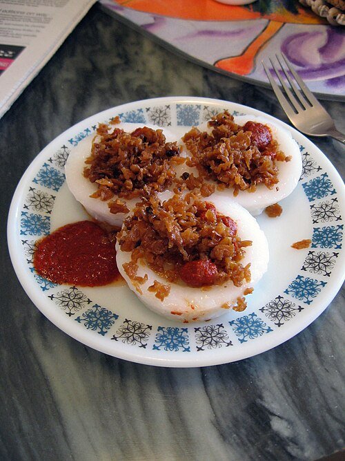 Plate of chwee kueh topped with preserved radish and chilli