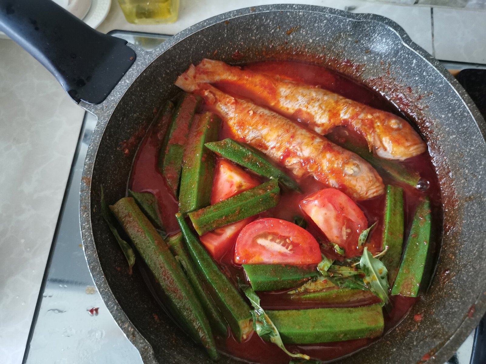 Ikan kerisi bersama bendi dan tomato dalam kuah asam pedas di dalam kuali