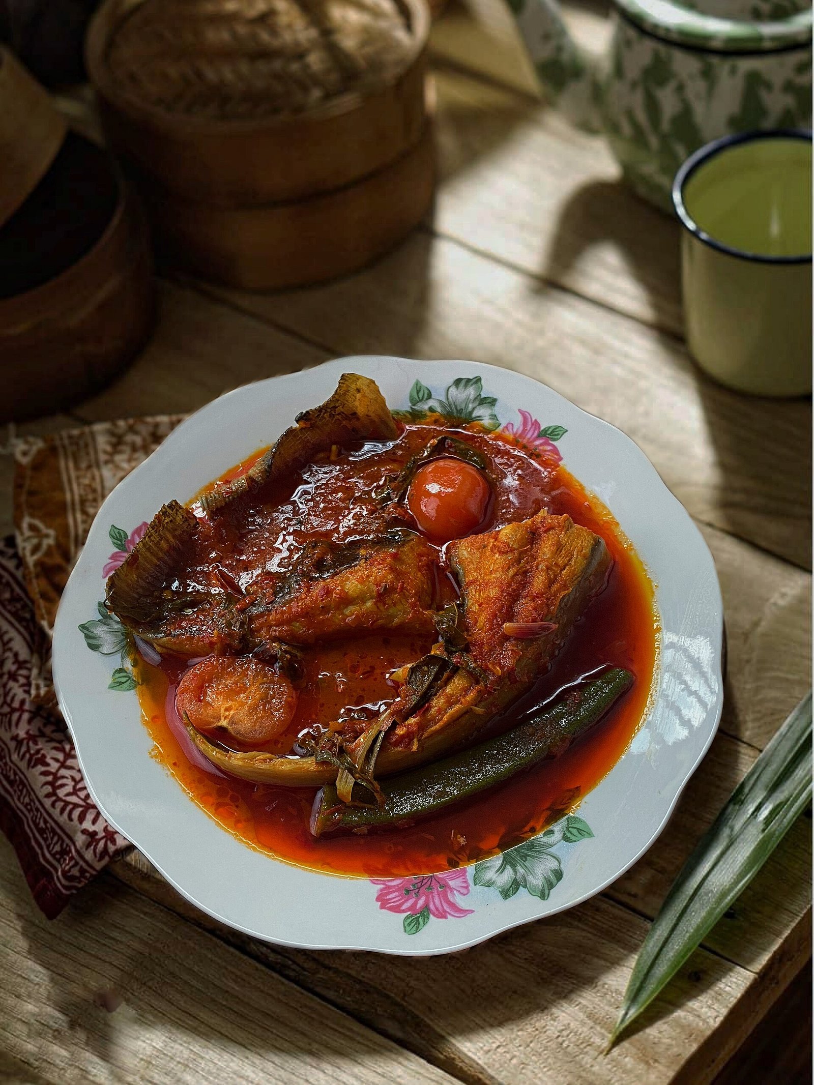 Asam pedas ikan pari berkuah merah di dalam pinggan dengan bendi