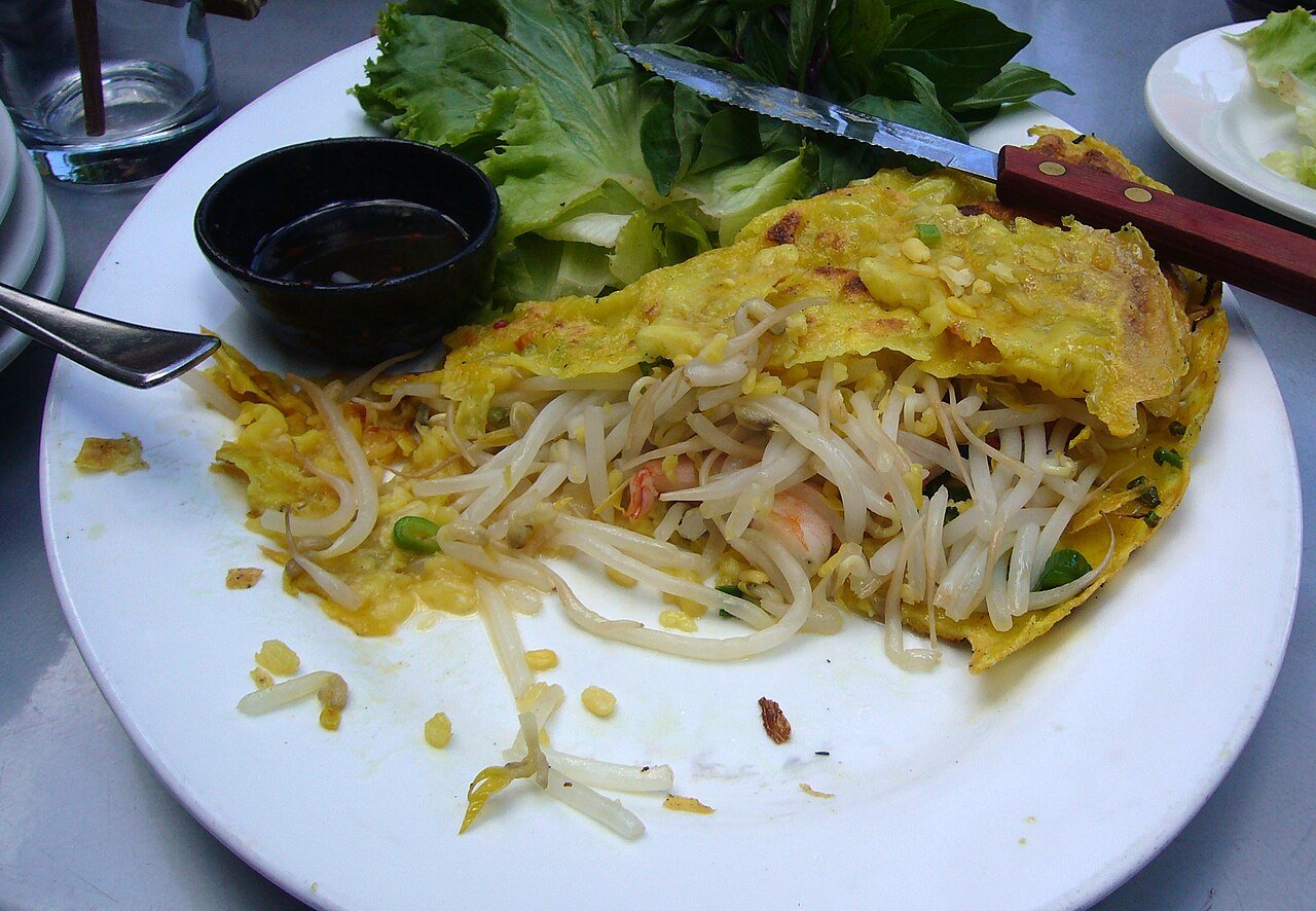 A separate bánh xèo serving with a folded golden crepe and vegetables