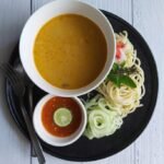 Laksa Johor dengan spageti, kuah ikan, timun dan sambal di atas pinggan