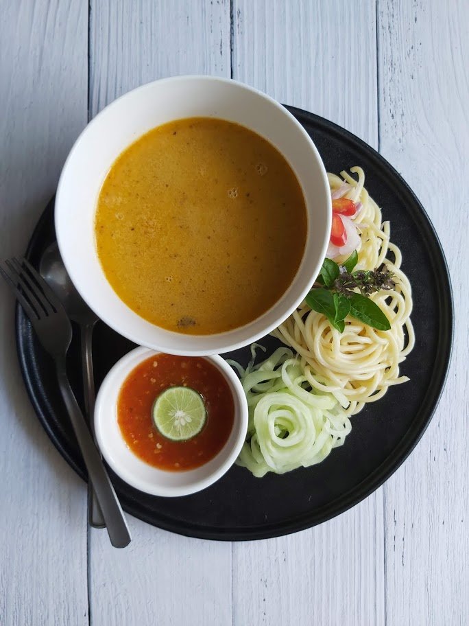 Laksa Johor dengan spageti, kuah ikan, timun dan sambal di atas pinggan