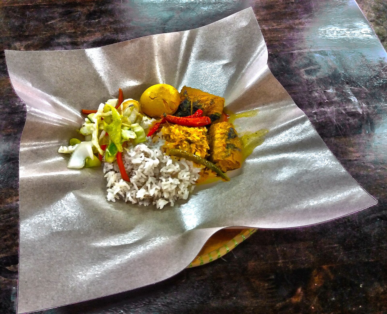 Nasi dagang dengan ikan, telur dan acar disaji di atas kertas pembungkus