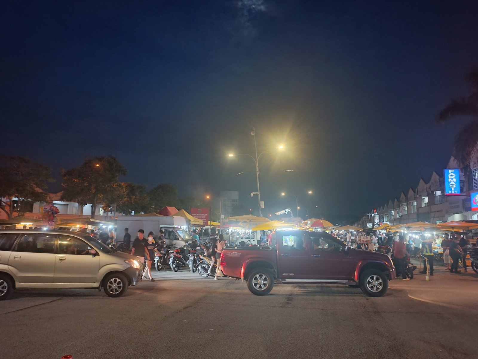 Deretan gerai pasar malam Seri Kembangan dengan pengunjung dan kenderaan