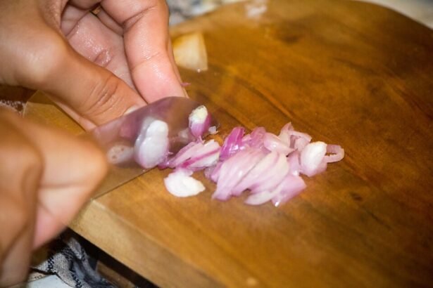 Cook chopping shallots on a wooden cutting board