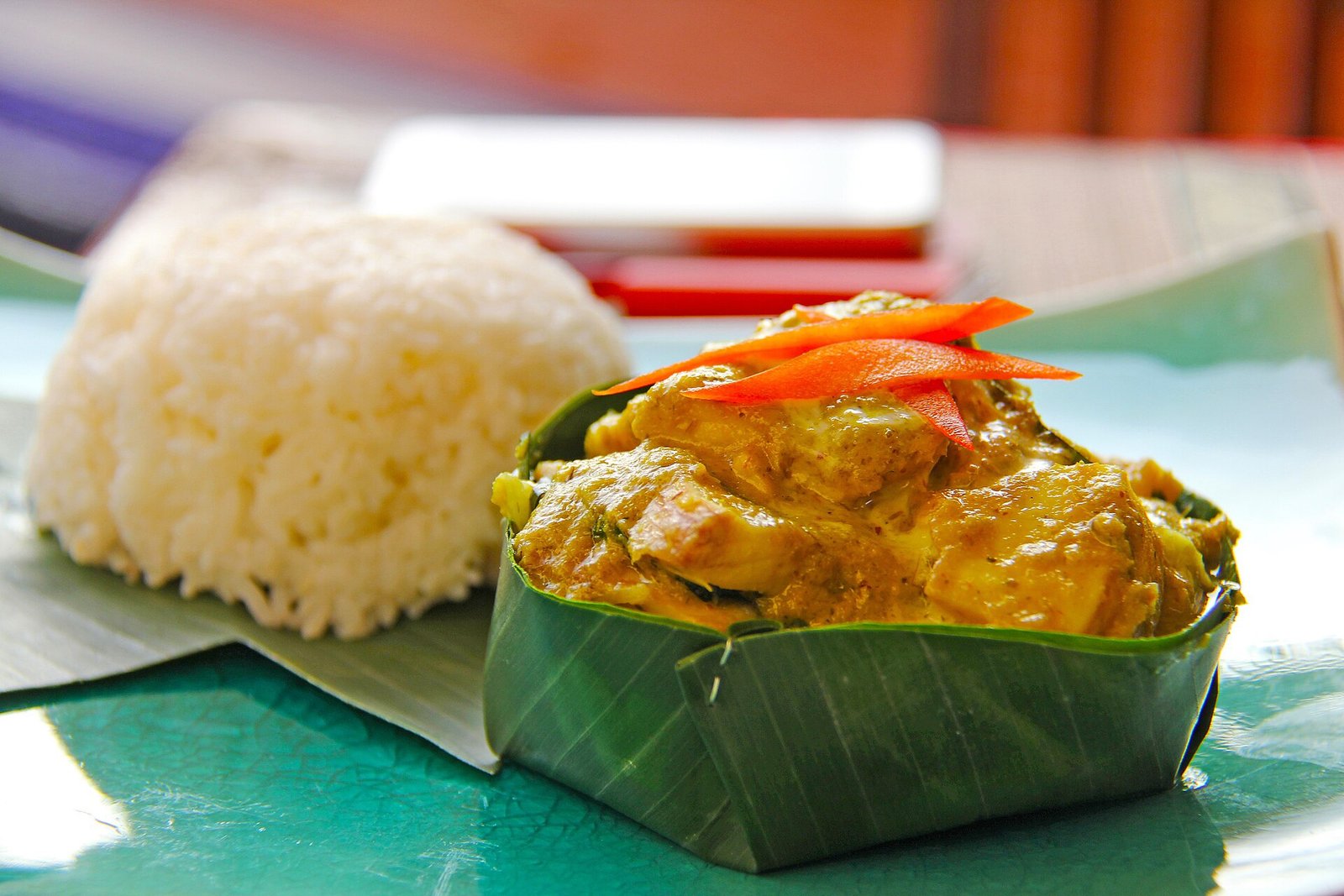 Fish amok in a leaf cup served beside a mound of white rice