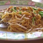 Semangkuk mee rebus dengan kuah dan pelengkap